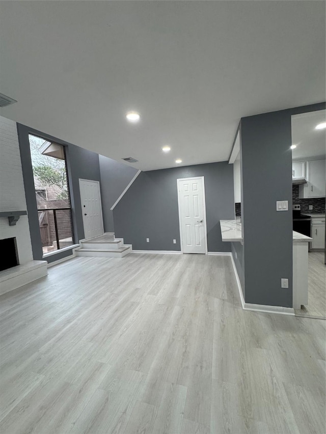 unfurnished living room featuring a large fireplace and light hardwood / wood-style floors