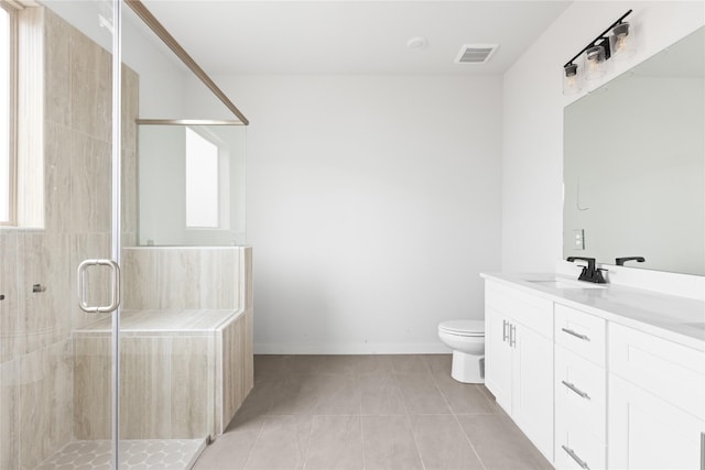 bathroom featuring tile patterned flooring, vanity, a shower with shower door, and toilet