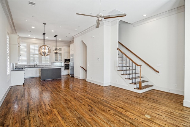 kitchen with a kitchen island, dark hardwood / wood-style floors, white cabinetry, hanging light fixtures, and crown molding