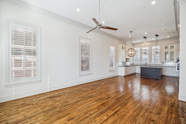 unfurnished living room featuring crown molding, dark hardwood / wood-style flooring, ceiling fan with notable chandelier, and sink