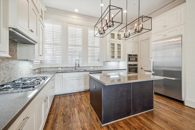 kitchen with sink, appliances with stainless steel finishes, white cabinetry, a center island, and light stone countertops