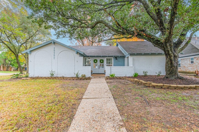 ranch-style home featuring a front lawn and french doors