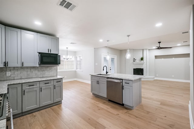 kitchen featuring sink, gray cabinets, a brick fireplace, decorative light fixtures, and stainless steel dishwasher