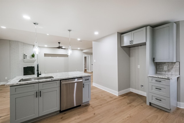 kitchen with pendant lighting, sink, gray cabinetry, stainless steel dishwasher, and light stone counters