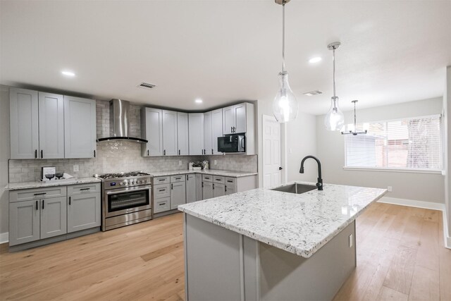 kitchen featuring sink, gray cabinetry, stainless steel stove, and wall chimney exhaust hood