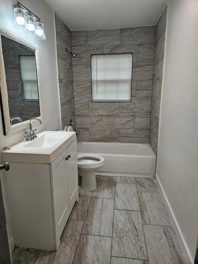 full bathroom featuring tiled shower / bath combo, vanity, and toilet