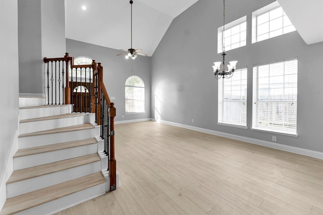 stairway featuring hardwood / wood-style flooring, ceiling fan with notable chandelier, and high vaulted ceiling