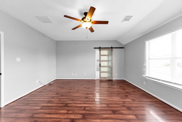 unfurnished room with dark wood-type flooring, ceiling fan, a barn door, and vaulted ceiling