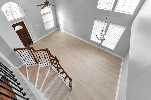 entrance foyer featuring a high ceiling, ceiling fan with notable chandelier, and hardwood / wood-style floors