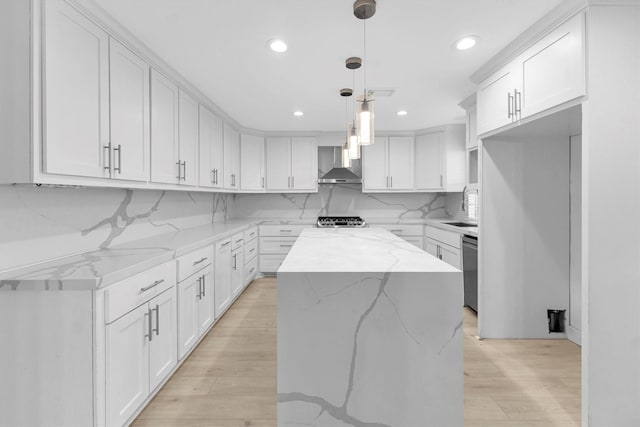 kitchen featuring wall chimney range hood, a center island, and white cabinets