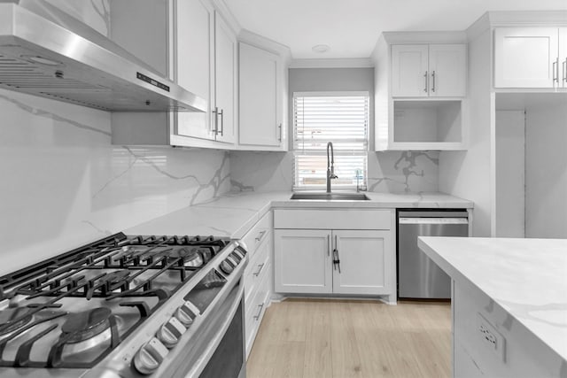 kitchen featuring white cabinetry, sink, stainless steel appliances, light stone countertops, and wall chimney range hood