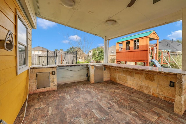 view of patio / terrace featuring ceiling fan and a playground