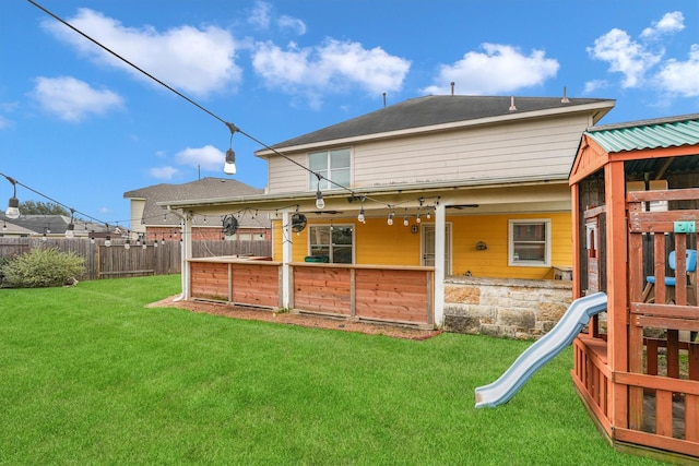 rear view of property with a lawn and a playground