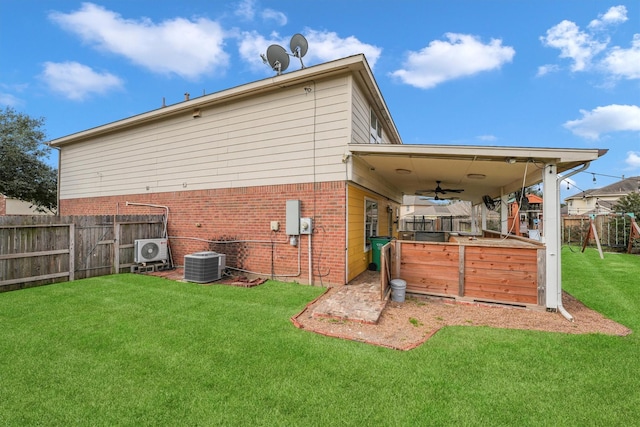 rear view of property with ac unit, ceiling fan, a yard, central air condition unit, and a jacuzzi