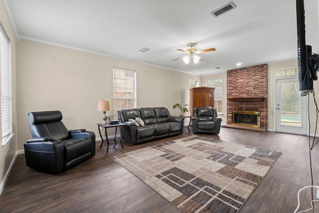 living room with dark wood-type flooring, ornamental molding, and a fireplace