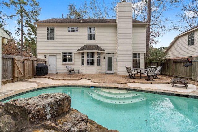 rear view of property featuring a fenced in pool, a fire pit, and a patio