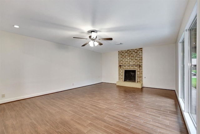 unfurnished living room featuring a fireplace, light hardwood / wood-style floors, and ceiling fan