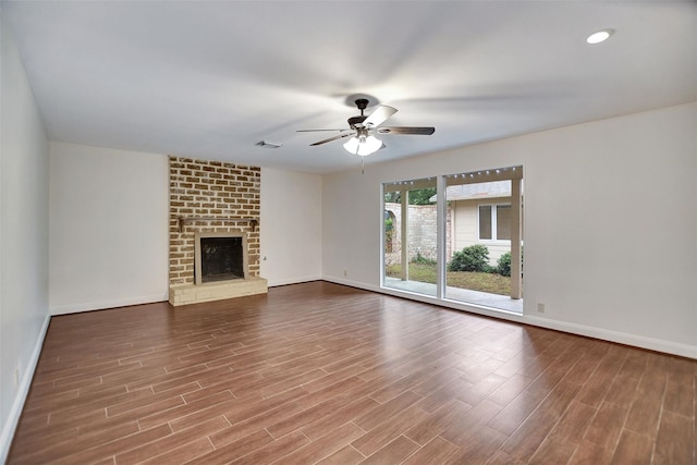 unfurnished living room with a brick fireplace, hardwood / wood-style floors, and ceiling fan