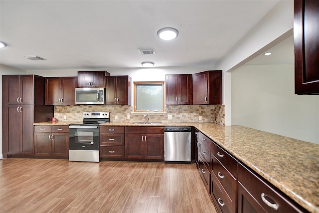 kitchen with sink, light hardwood / wood-style flooring, appliances with stainless steel finishes, kitchen peninsula, and decorative backsplash