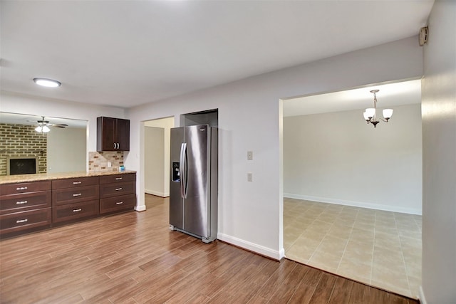 kitchen featuring ceiling fan with notable chandelier, decorative light fixtures, tasteful backsplash, stainless steel fridge, and dark brown cabinetry