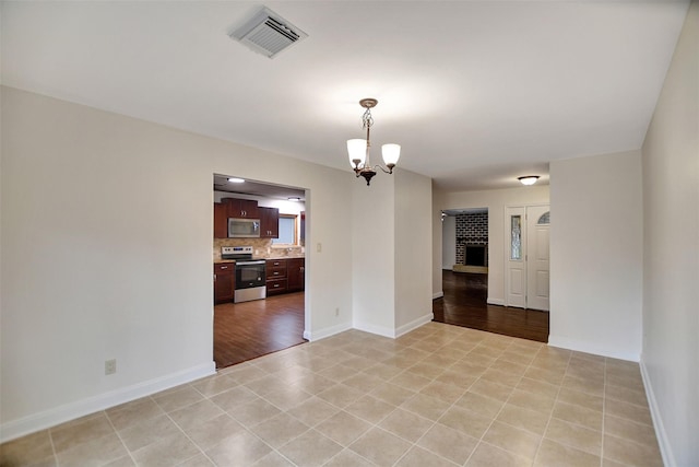 tiled empty room featuring a notable chandelier