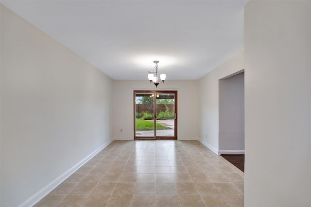 empty room with an inviting chandelier and light tile patterned floors