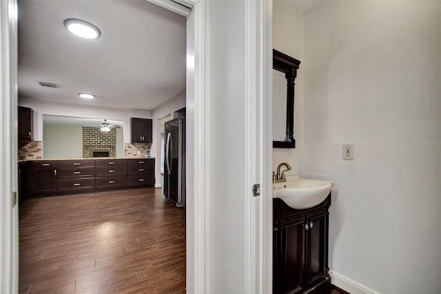 bathroom featuring ceiling fan, vanity, hardwood / wood-style floors, and backsplash