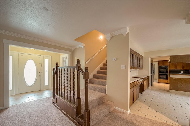 carpeted entrance foyer with ornamental molding and a textured ceiling