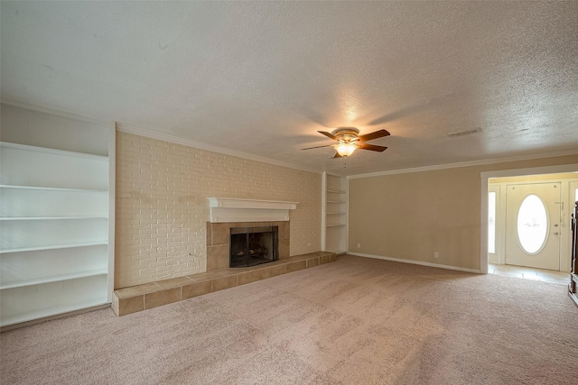 unfurnished living room with a tile fireplace, carpet, ornamental molding, and a textured ceiling