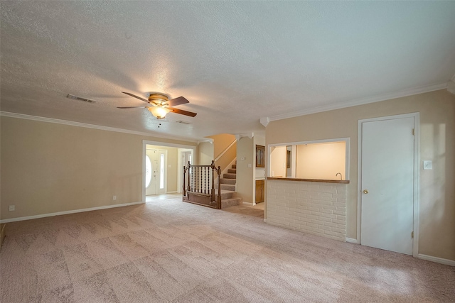 unfurnished living room with ceiling fan, ornamental molding, light carpet, and a textured ceiling