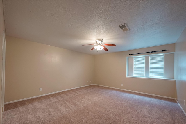 carpeted spare room with a textured ceiling and ceiling fan