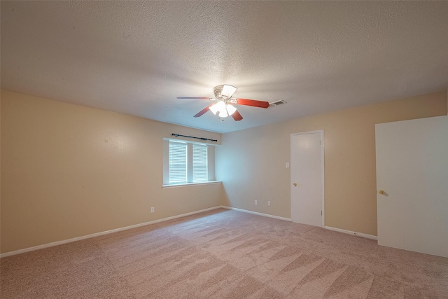 unfurnished room featuring ceiling fan, light colored carpet, and a textured ceiling