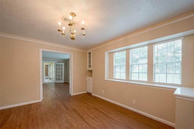 interior space with an inviting chandelier, wood-type flooring, crown molding, and a textured ceiling