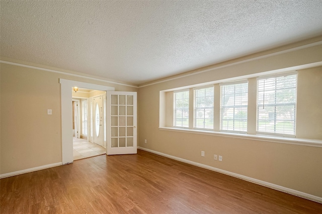 empty room featuring crown molding, a healthy amount of sunlight, and light hardwood / wood-style floors