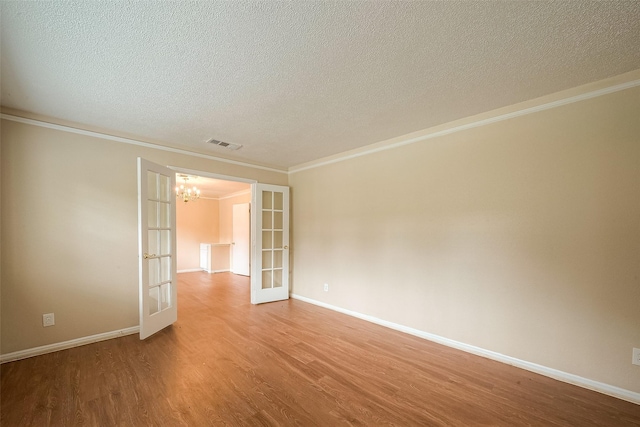 empty room with crown molding, hardwood / wood-style flooring, french doors, and a textured ceiling