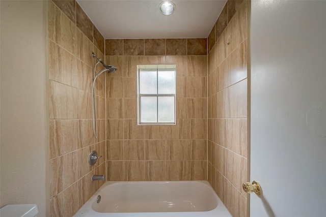 bathroom featuring toilet and tiled shower / bath combo