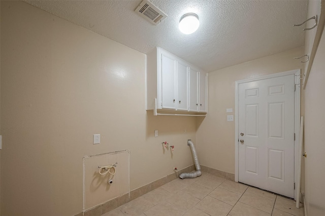 washroom featuring cabinets, gas dryer hookup, light tile patterned flooring, and a textured ceiling