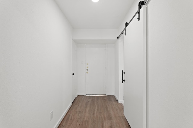 hall with a barn door and light wood-type flooring