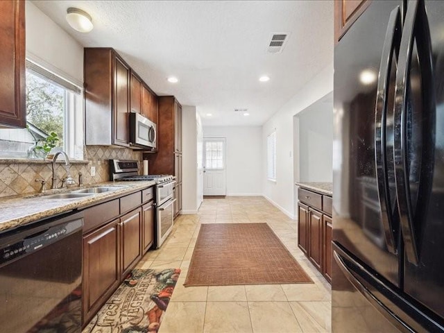 kitchen featuring tasteful backsplash, a healthy amount of sunlight, light tile patterned floors, and black appliances