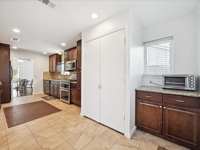 kitchen featuring stainless steel appliances, light tile patterned flooring, a healthy amount of sunlight, and backsplash