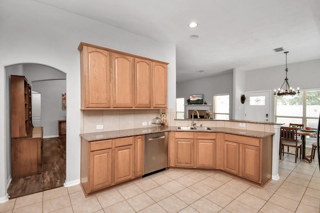 kitchen featuring light stone counters, stainless steel dishwasher, sink, and light tile patterned floors