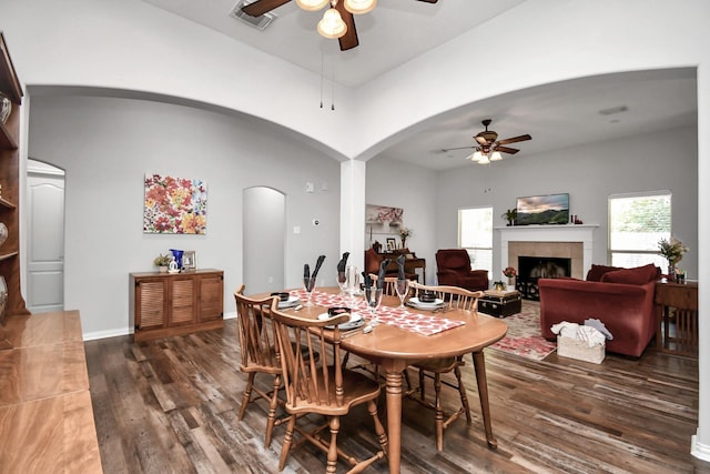 dining space with ceiling fan, a fireplace, and dark hardwood / wood-style flooring