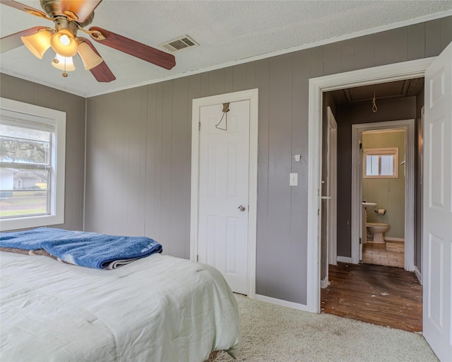 bedroom with crown molding, connected bathroom, a textured ceiling, and ceiling fan