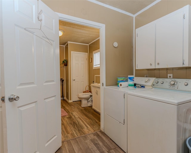 washroom with cabinets, crown molding, light hardwood / wood-style flooring, and washer and dryer