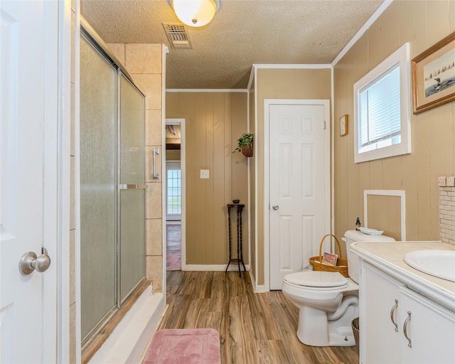 bathroom with hardwood / wood-style flooring, walk in shower, toilet, crown molding, and a textured ceiling