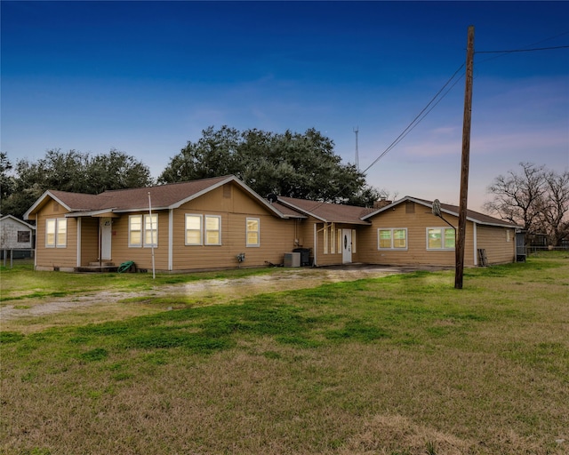 view of front of property with central AC unit and a lawn