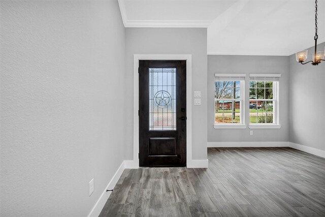 foyer featuring crown molding, hardwood / wood-style floors, and an inviting chandelier