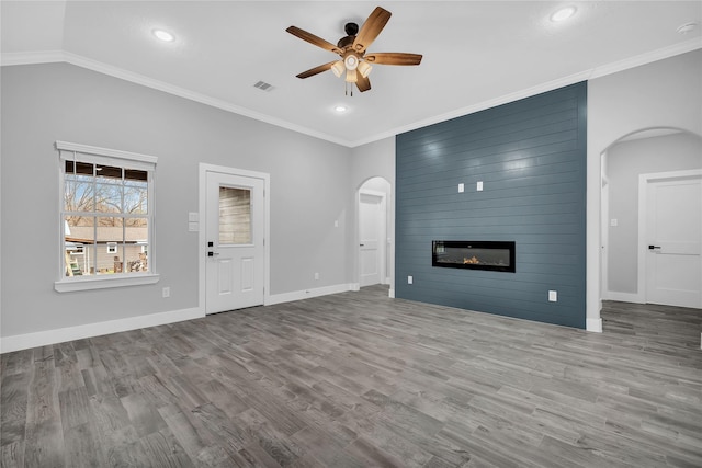 unfurnished living room featuring ornamental molding, a large fireplace, ceiling fan, and light wood-type flooring