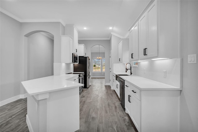 kitchen featuring appliances with stainless steel finishes, tasteful backsplash, wood-type flooring, ornamental molding, and white cabinets