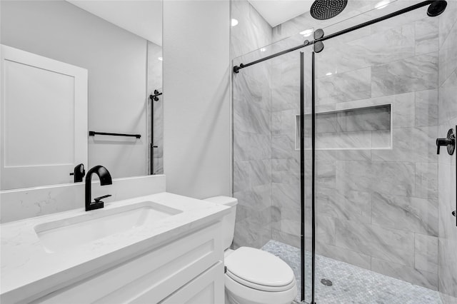 bathroom with toilet, vanity, and a shower with shower door